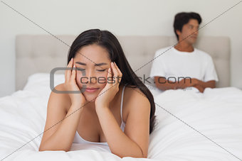 Woman lying on bed with boyfriend sitting