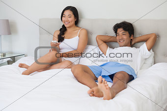 Happy couple lying on bed together watching tv