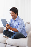 Happy man sitting on couch using tablet