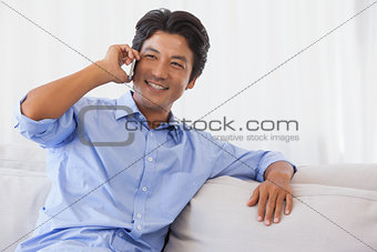 Happy man sitting on couch on the phone