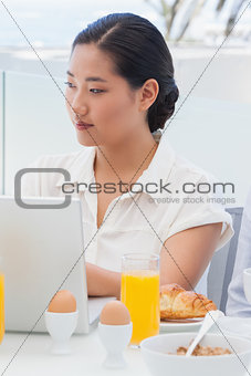 Woman using her laptop at breakfast