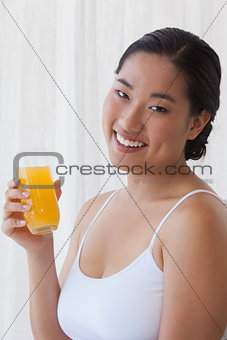 Pretty asian woman holding glass of orange juice