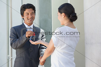 Smiling estate agent giving the key to buyer