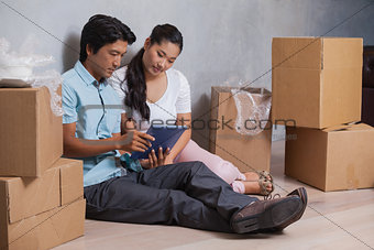 Happy couple sitting on floor using tablet