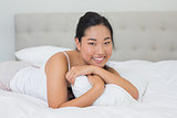 Smiling asian woman lying on bed