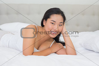 Smiling asian woman lying on bed