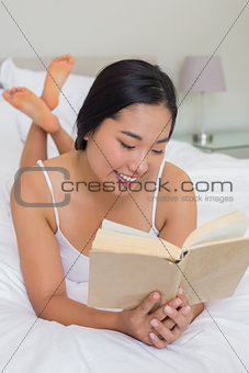 Smiling woman lying on bed reading