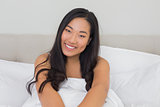 Smiling woman lying in bed in the morning