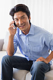 Happy man sitting on couch talking on phone