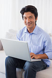 Happy man sitting on couch using laptop