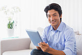 Happy man sitting on couch using tablet pc
