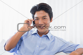 Happy man relaxing on couch talking on phone