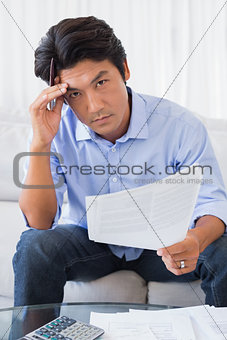 Man sitting on couch working out his finances