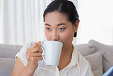 Smiling woman sitting on couch having coffee