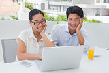 Smiling couple having breakfast together using laptop