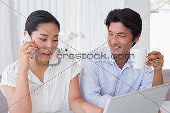 Couple using laptop with woman talking on phone