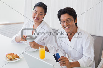 Couple in bathrobes shopping online in the morning