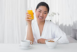 Happy woman in bathrobe having her breakfast