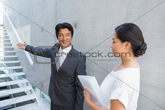 Estate agent showing stairs to customer and smiling