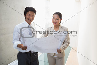 Estate agent looking at blueprint with potential buyer
