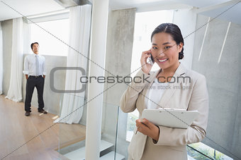 Estate agent talking on phone with buyer in background