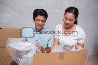 Happy couple sitting on floor unpacking boxes