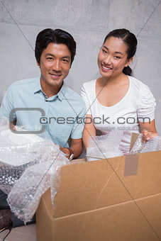 Happy couple sitting on floor unpacking boxes