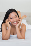Happy woman lying on bed on a phone call