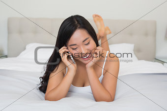 Shocked woman lying on bed talking on the phone