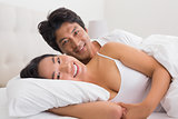 Smiling couple lying in bed