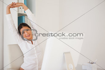 Casual businesswoman stretching at her desk