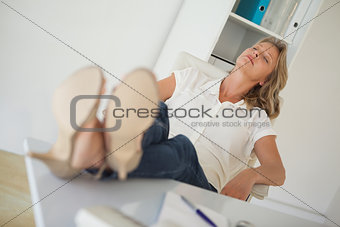 Casual businesswoman sitting at her desk with feet up