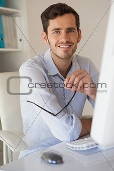 Casual businessman smiling at camera at his desk