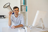 Casual businessman sitting at desk with megaphone