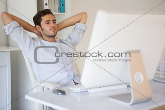 Casual businessman relaxing at desk leaning back