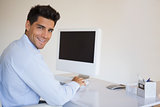 Casual businessman working at his desk smiling at camera