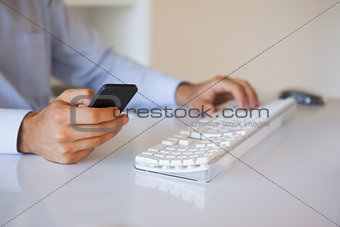 Businessman texting on phone at desk