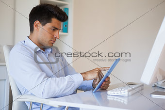Casual businessman working on his tablet at his desk