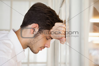 Casual worried businessman leaning against the window