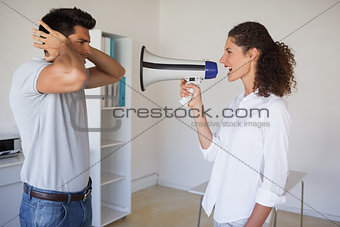 Casual businesswoman shouting at colleague through megaphone