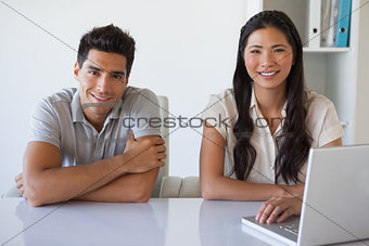 Casual business team using laptop together at desk