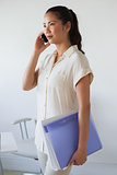 Casual businesswoman on the phone holding folder