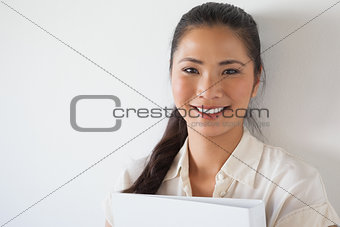 Casual businesswoman smiling at camera holding folder