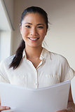 Casual businesswoman holding document and smiling at camera