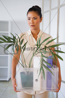 Fired businesswoman holding box of her things