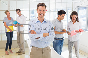Casual boss smiling at camera in front of business team