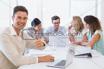Casual business team having a meeting with man giving thumbs up