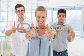 Casual business team smiling at camera with thumbs up