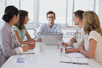 Casual boss smiling at camera dueing meeting with business team