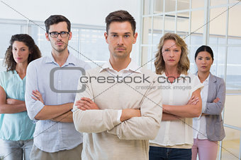 Casual business team frowning at camera with arms crossed